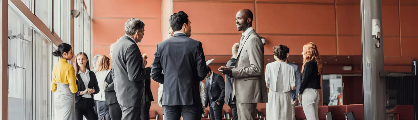 Des professionnels en discussion dans un espace de conférence moderne, illustrant l'importance du networking pour élargir son réseau