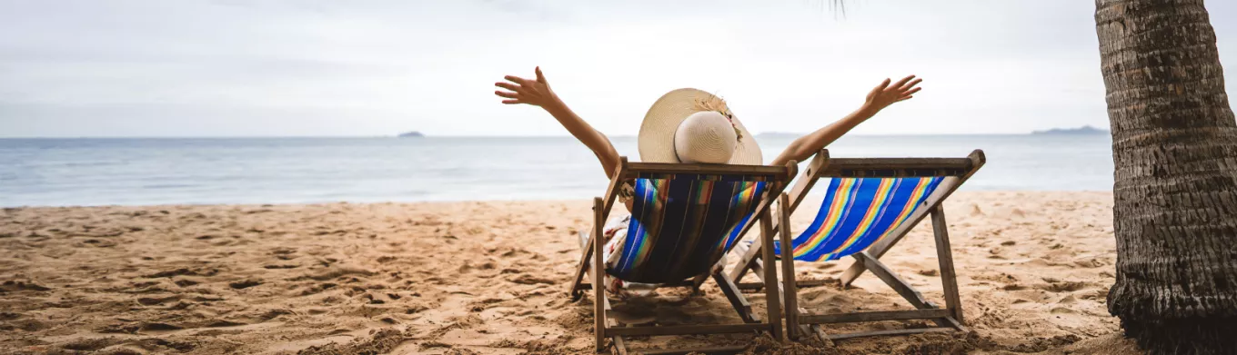 Personne détendue sur une chaise longue face à la mer, symbole de la déconnexion pendant les vacances – Pluxee Luxembourg 