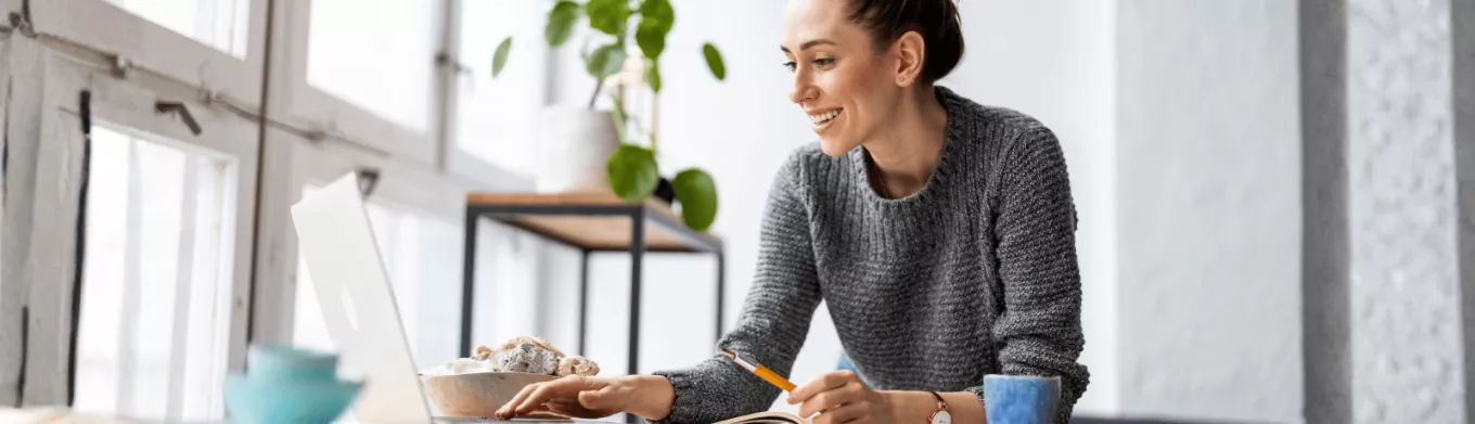 Une femme souriante à son bureau devant son écran d'ordinateur 