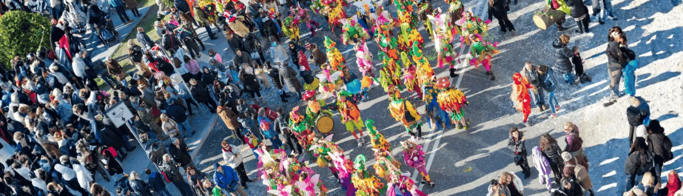Des personnes défilant pour le carnaval au Luxembourg dans la rue avec un public qui regarde le défilé 