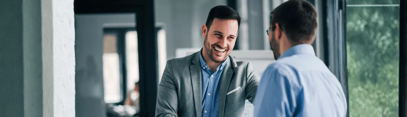 Deux hommes se serrant la main en entreprise à l'occasion d'une entrée en fonction avant transmettre la culture de l'entreprise