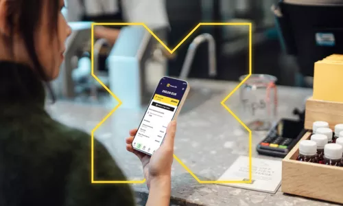 Femme tenant son téléphone ouvert sur l'application Pluxee sur le solde de sa carte Pluxee Gift