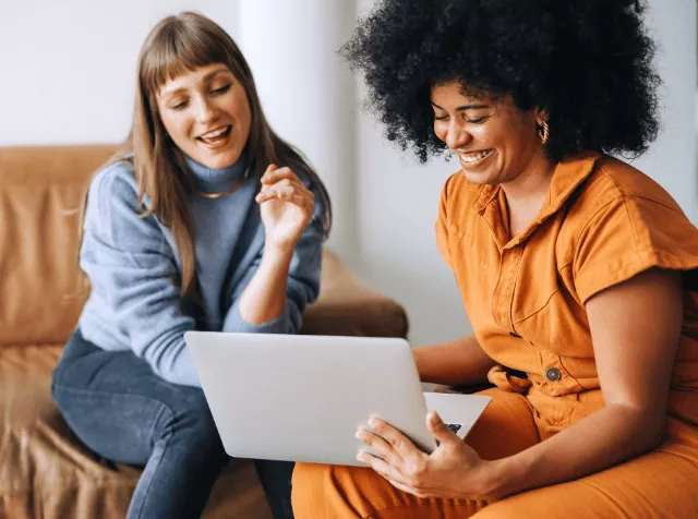 Deux collaboratrices discutant autour d’un ordinateur portable – Pluxee Luxembourg propose un accompagnement personnalisé pour faciliter l’octroi et la gestion des chèques-repas dans votre entreprise. Simplifiez vos démarches dès aujourd’hui.