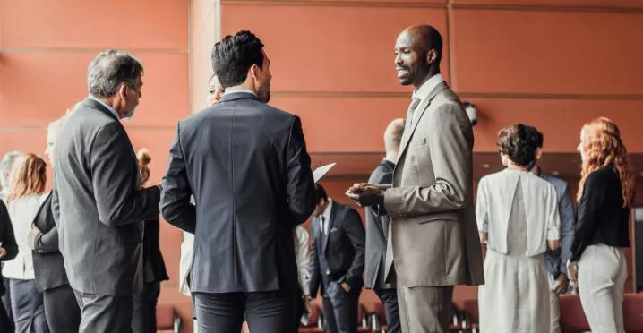Des professionnels en discussion dans un espace de conférence moderne, illustrant l'importance du networking pour élargir son réseau