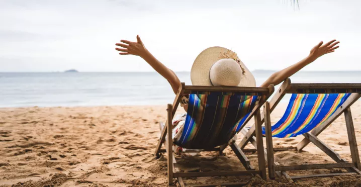 Personne détendue sur une chaise longue face à la mer, symbole de la déconnexion pendant les vacances – Pluxee Luxembourg