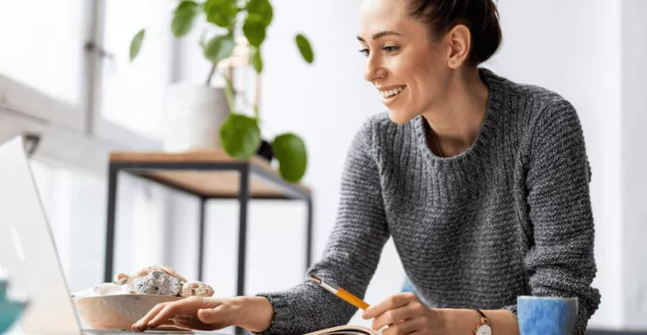 Une femme souriante à son bureau devant son écran d'ordinateur