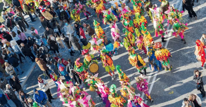Des personnes défilant pour le carnaval au Luxembourg dans la rue avec un public qui regarde le défilé