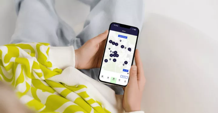 Une femme tenant un smartphone dans ses mains avec l'application Pluxee ouverte sur son Store Locator au Luxembourg