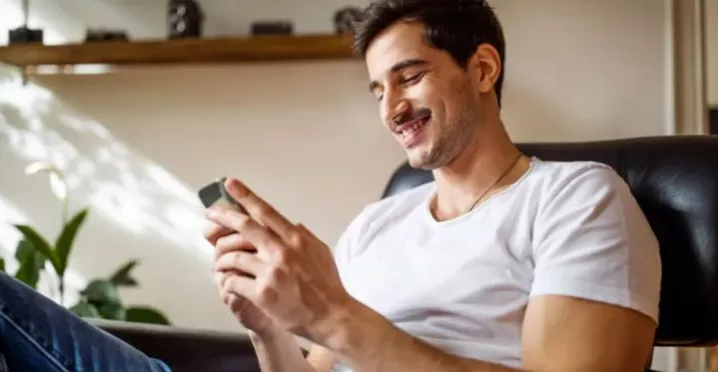 Personne consultant une application mobile sur son smartphone depuis son domicile.