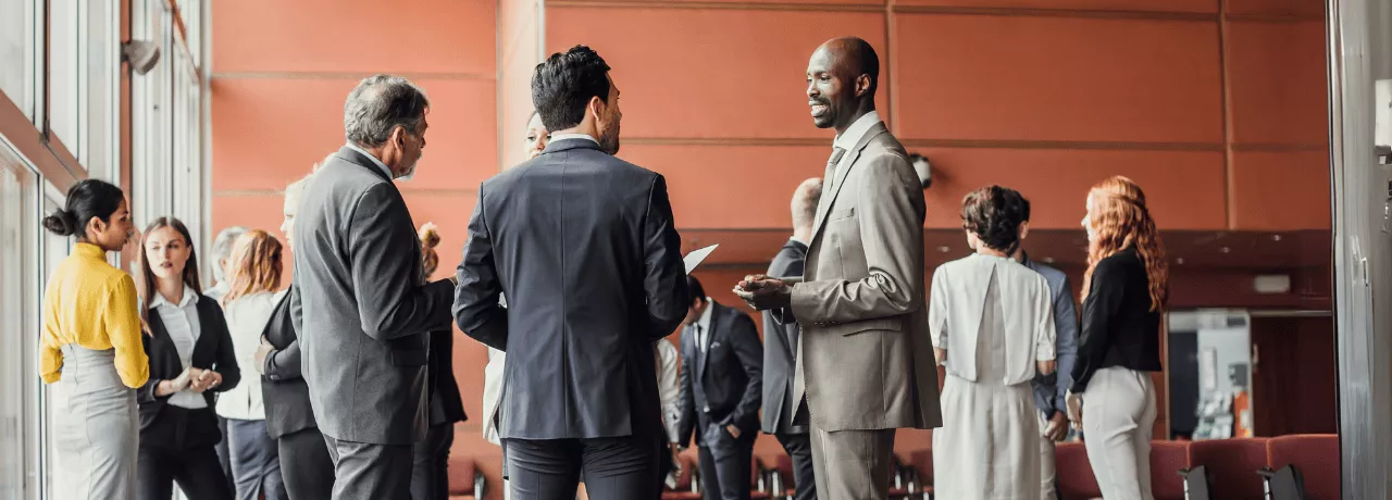 Des professionnels en discussion dans un espace de conférence moderne, illustrant l'importance du networking pour élargir son réseau
