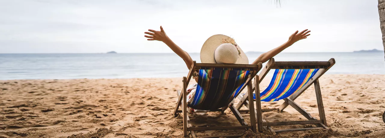 Personne détendue sur une chaise longue face à la mer, symbole de la déconnexion pendant les vacances – Pluxee Luxembourg