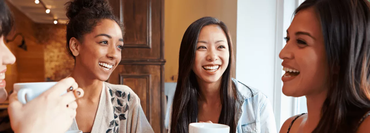 Groupe de femmes souriantes partageant un café, symbole de convivialité et d’intégration sociale pour les nouveaux arrivants au Luxembourg