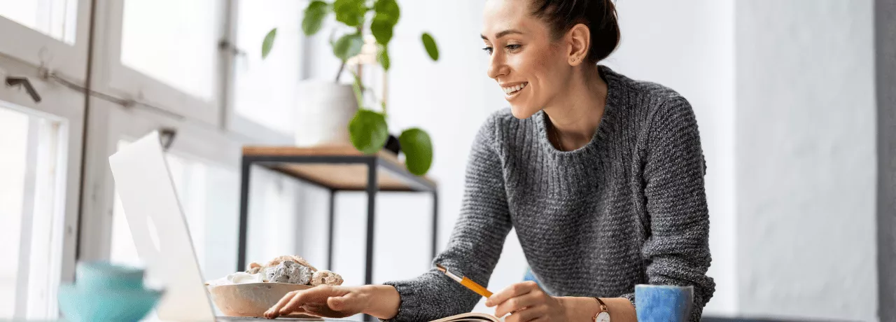 Une femme souriante à son bureau devant son écran d'ordinateur