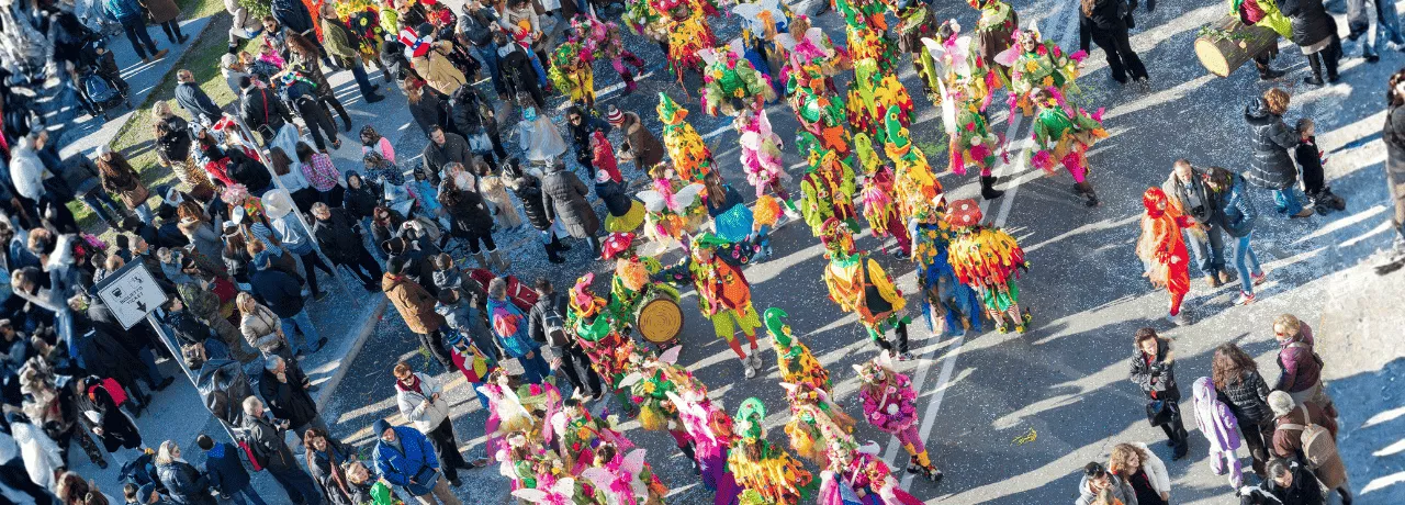 Des personnes défilant pour le carnaval au Luxembourg dans la rue avec un public qui regarde le défilé
