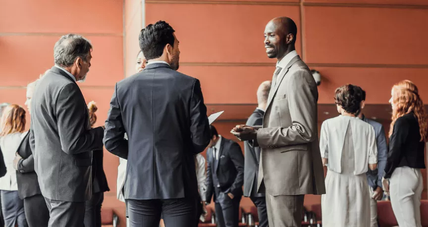 Des professionnels en discussion dans un espace de conférence moderne, illustrant l'importance du networking pour élargir son réseau