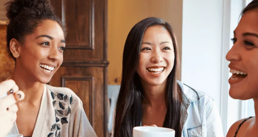 Groupe de femmes souriantes partageant un café, symbole de convivialité et d’intégration sociale pour les nouveaux arrivants au Luxembourg