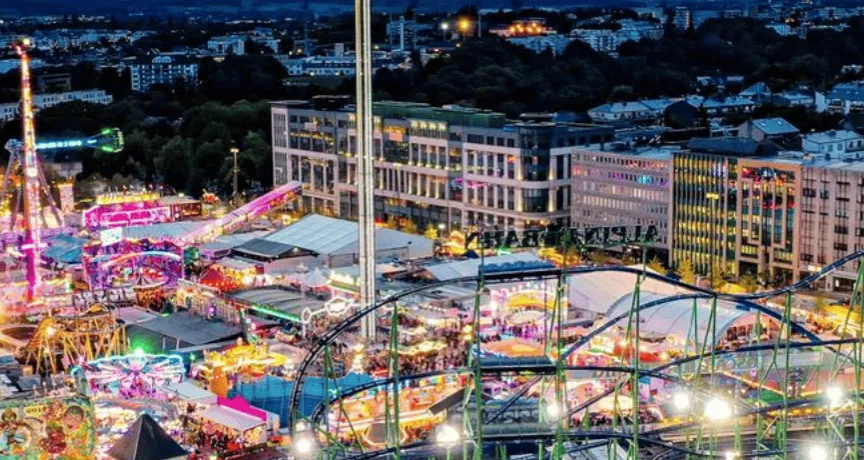 Schueberfouer Luxembourg au coucher du soleil avec grande roue illuminée, manèges et attractions: idée de sortie familiale avant la rentrée scolaire, recommandée par Pluxee Luxembourg.