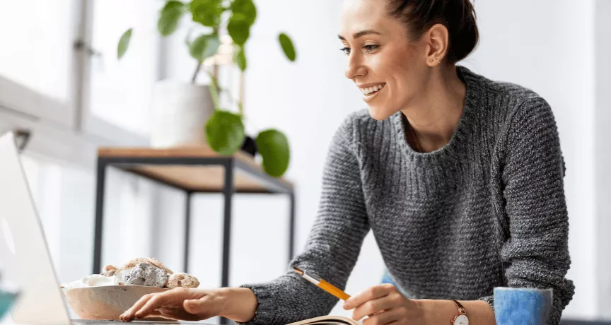 Une femme souriante à son bureau devant son écran d'ordinateur