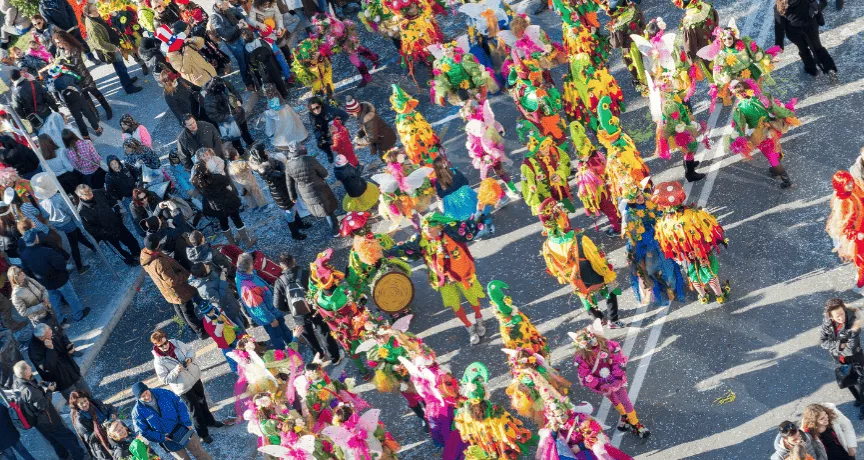 Des personnes défilant pour le carnaval au Luxembourg dans la rue avec un public qui regarde le défilé