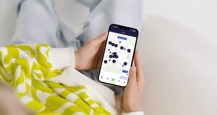Une femme tenant un smartphone dans ses mains avec l'application Pluxee ouverte sur son Store Locator au Luxembourg