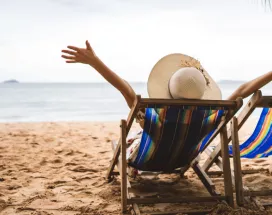 Personne détendue sur une chaise longue face à la mer, symbole de la déconnexion pendant les vacances – Pluxee Luxembourg