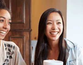 Groupe de femmes souriantes partageant un café, symbole de convivialité et d’intégration sociale pour les nouveaux arrivants au Luxembourg