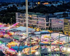 Schueberfouer Luxembourg au coucher du soleil avec grande roue illuminée, manèges et attractions: idée de sortie familiale avant la rentrée scolaire, recommandée par Pluxee Luxembourg.