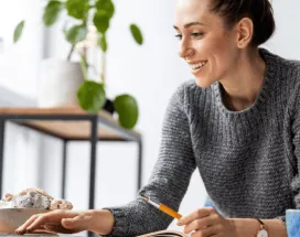 Une femme souriante à son bureau devant son écran d'ordinateur