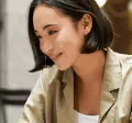 Femme souriante travaillant sur un ordinateur portable en terrasse - Pluxee Luxembourg, solutions pour le bien-être au travail