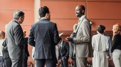 Des professionnels en discussion dans un espace de conférence moderne, illustrant l'importance du networking pour élargir son réseau