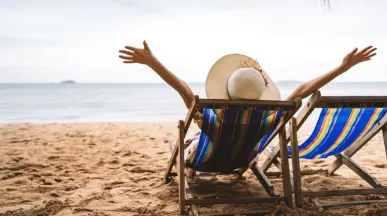 Personne détendue sur une chaise longue face à la mer, symbole de la déconnexion pendant les vacances – Pluxee Luxembourg