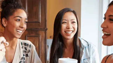Groupe de femmes souriantes partageant un café, symbole de convivialité et d’intégration sociale pour les nouveaux arrivants au Luxembourg