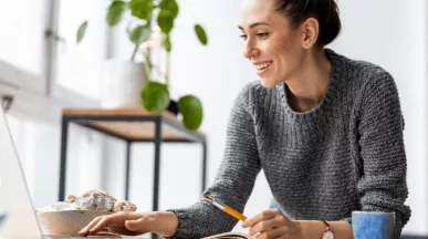 Une femme souriante à son bureau devant son écran d'ordinateur