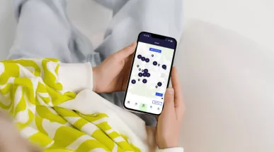 Une femme tenant un smartphone dans ses mains avec l'application Pluxee ouverte sur son Store Locator au Luxembourg