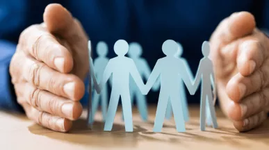 2 mains entourants de figures d'hommes et de femmes en papier représentant le RH qui veille sur ses équipes