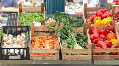 Étal de marché avec légumes frais, carottes, poivrons, champignons et herbes aromatiques.