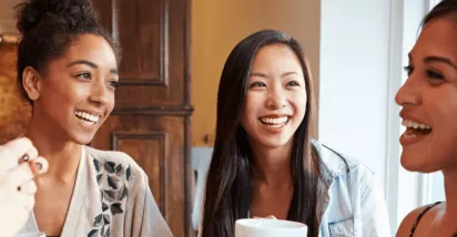 Groupe de femmes souriantes partageant un café, symbole de convivialité et d’intégration sociale pour les nouveaux arrivants au Luxembourg
