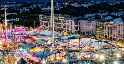 Schueberfouer Luxembourg au coucher du soleil avec grande roue illuminée, manèges et attractions: idée de sortie familiale avant la rentrée scolaire, recommandée par Pluxee Luxembourg.